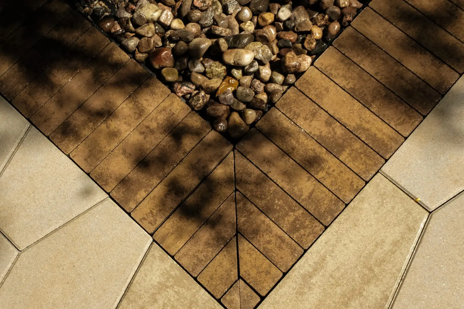 Close detail of the brick band mitred to a point around the river-stone inlay, the cuts meeting exactly at the corner