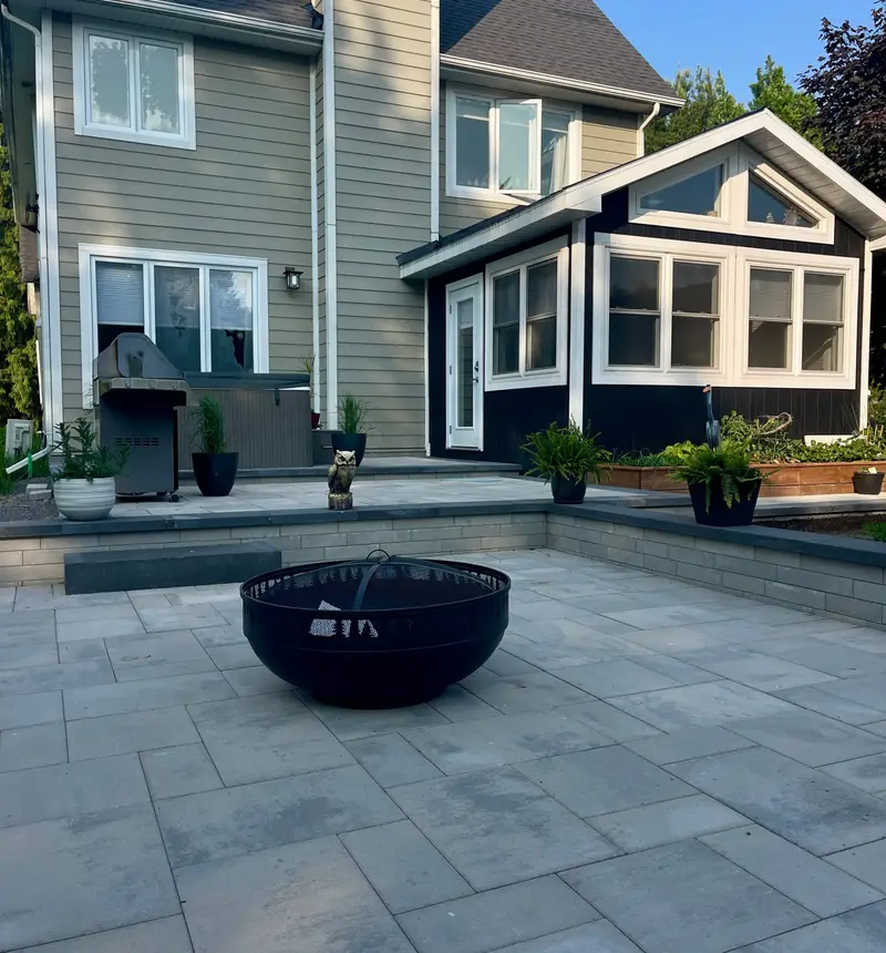 Completed interlock paver patio with a stacked-stone retaining wall and tight, level joints