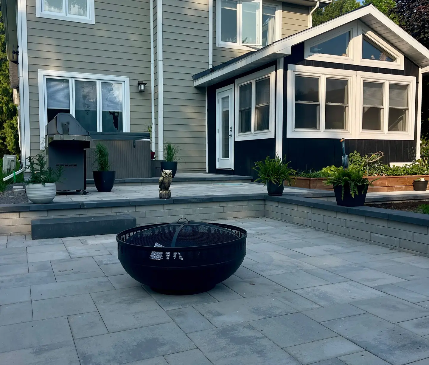 Completed interlock paver patio with a stacked-stone retaining wall and tight, level joints